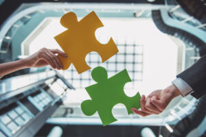Close-up of business people wanting to put two pieces of puzzle together.