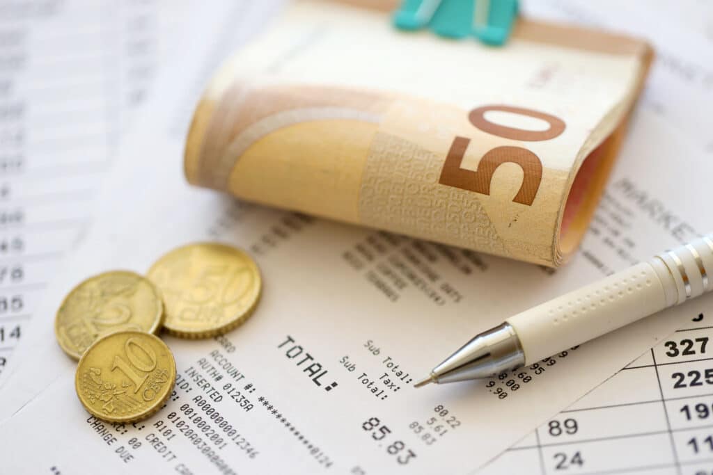 Heap of euro money bills in stationery clip on papers with calculations and receipts close up. Business and accounting concept